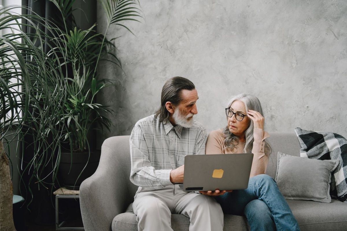Two adults over 50 talking closely on a sofa at home